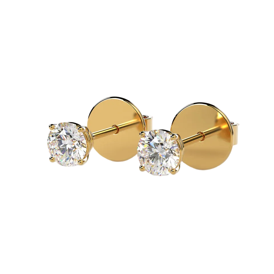 A pair of gold stud earrings with round brilliant-cut clear gemstones in a four-prong setting, shown on a light beige background.
