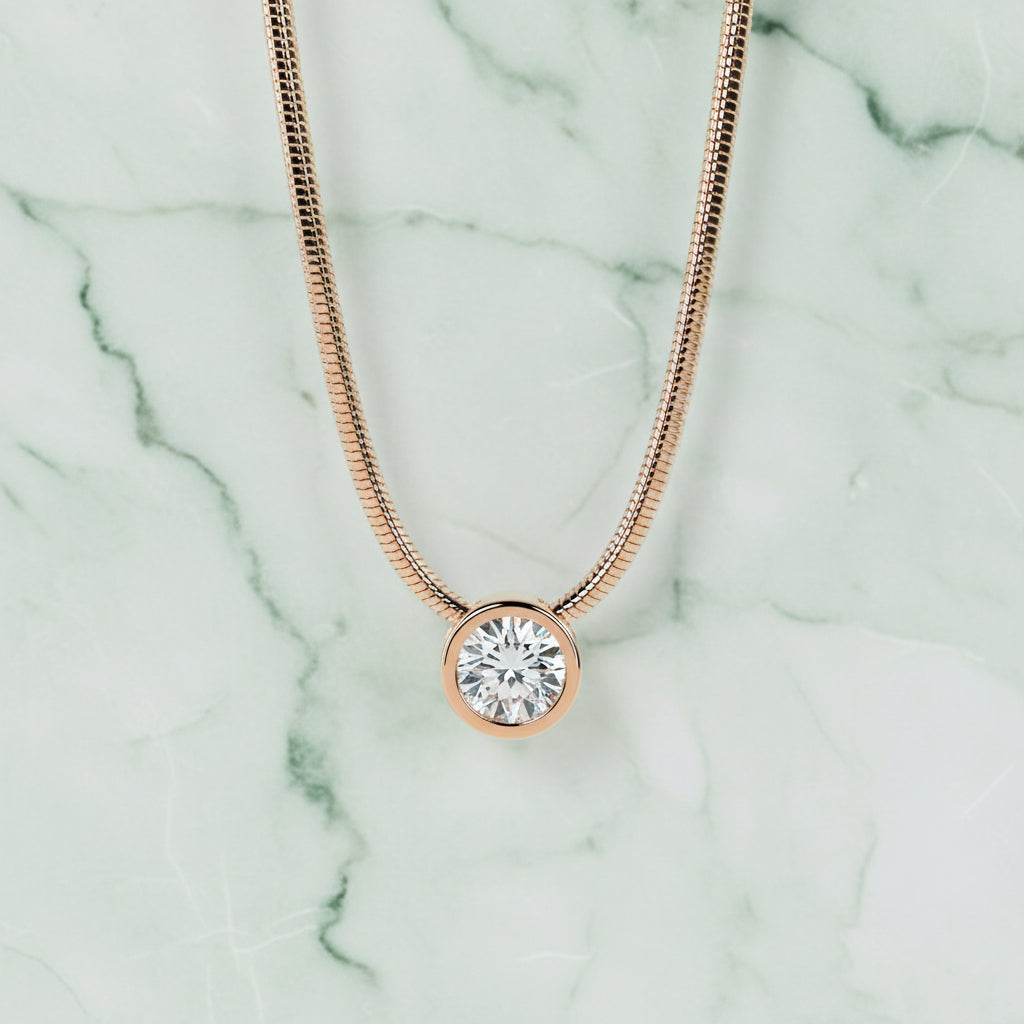Rose gold and silver necklace with a cube pendant on a light gray background