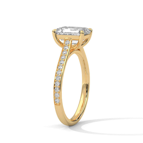 A yellow gold engagement ring featuring a large rectangular emerald-cut diamond center stone and a pavé-set diamond band, shown on a clean white background.