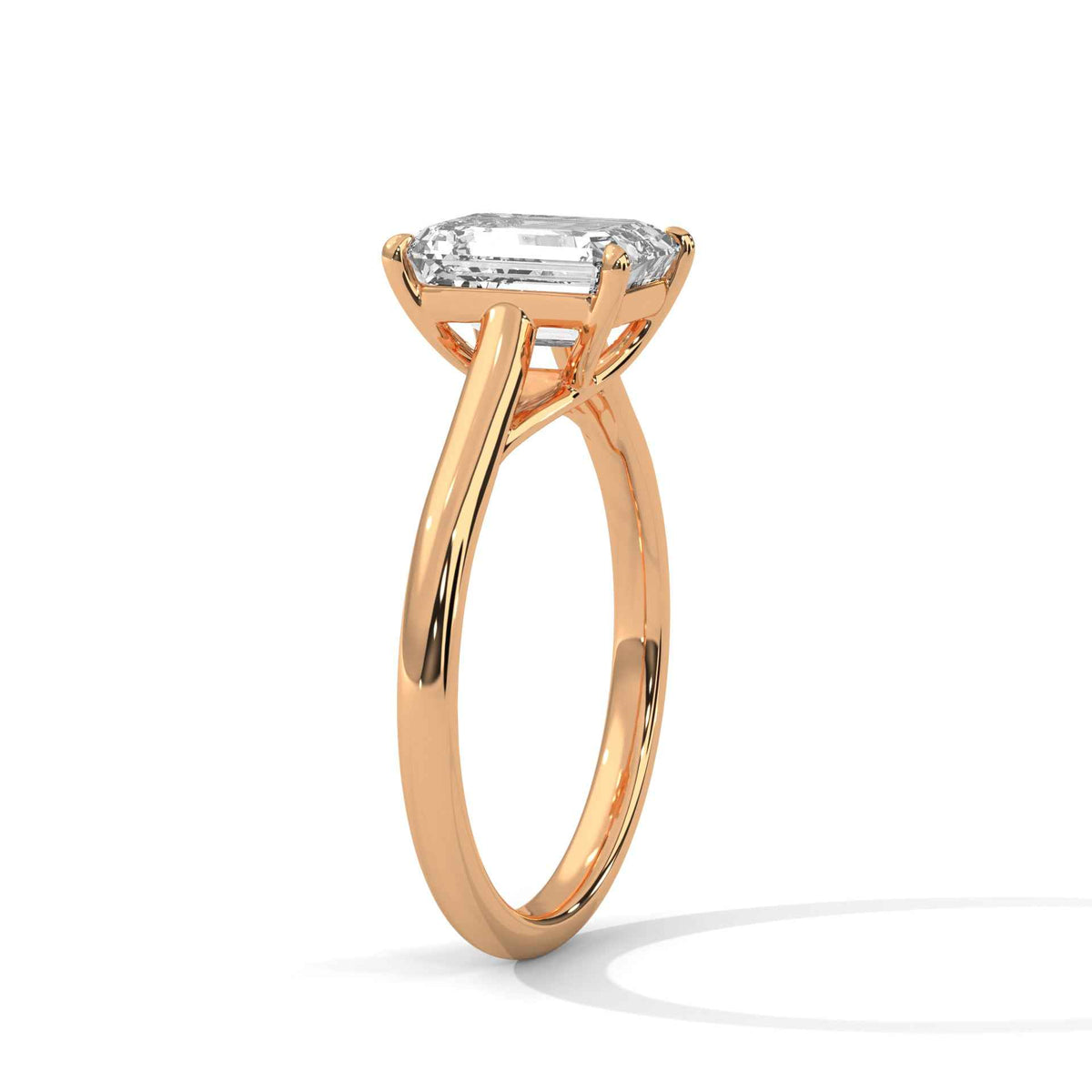A rose gold engagement ring featuring a large emerald-cut diamond solitaire, shown in a three-quarter side view on a clean white background with a soft shadow.