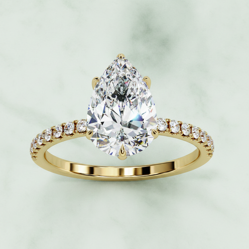 Gold ring with a pear-shaped diamond on a white background