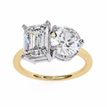 Two-stone diamond ring with emerald-cut and round-cut diamonds on a gold band.